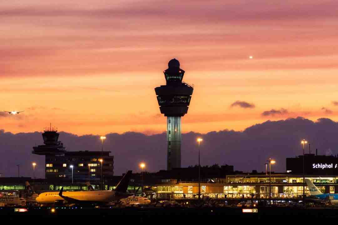 Escort Service Schiphol Airport at dusk with city lights in the background